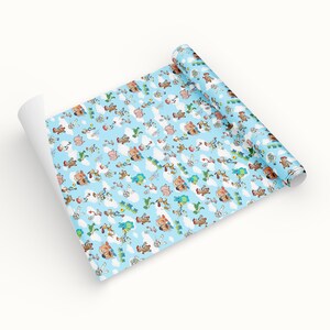 Puede incluir: Un rollo de papel de regalo azul claro con un patr&oacute;n repetido de personajes de dibujos animados, nubes y aviones. Los personajes son de varios colores y las nubes son blancas. El papel est&aacute; parcialmente desenrollado.