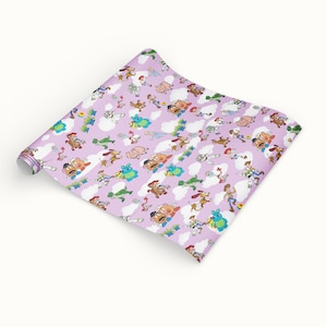 May include: A roll of lavender wrapping paper featuring a repeating pattern of cartoon characters, including Woody, Buzz Lightyear, and Mr. Potato Head, with white cloud accents. The paper is unrolled, showing the full design.