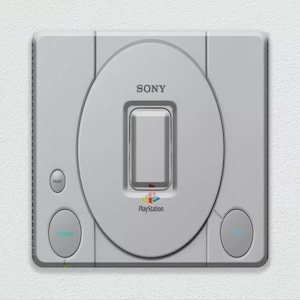May include: A white Sony PlayStation console with a grey disc drive, a power button, a reset button, and an open button. The console has the PlayStation logo and the text "PlayStation" on the front.