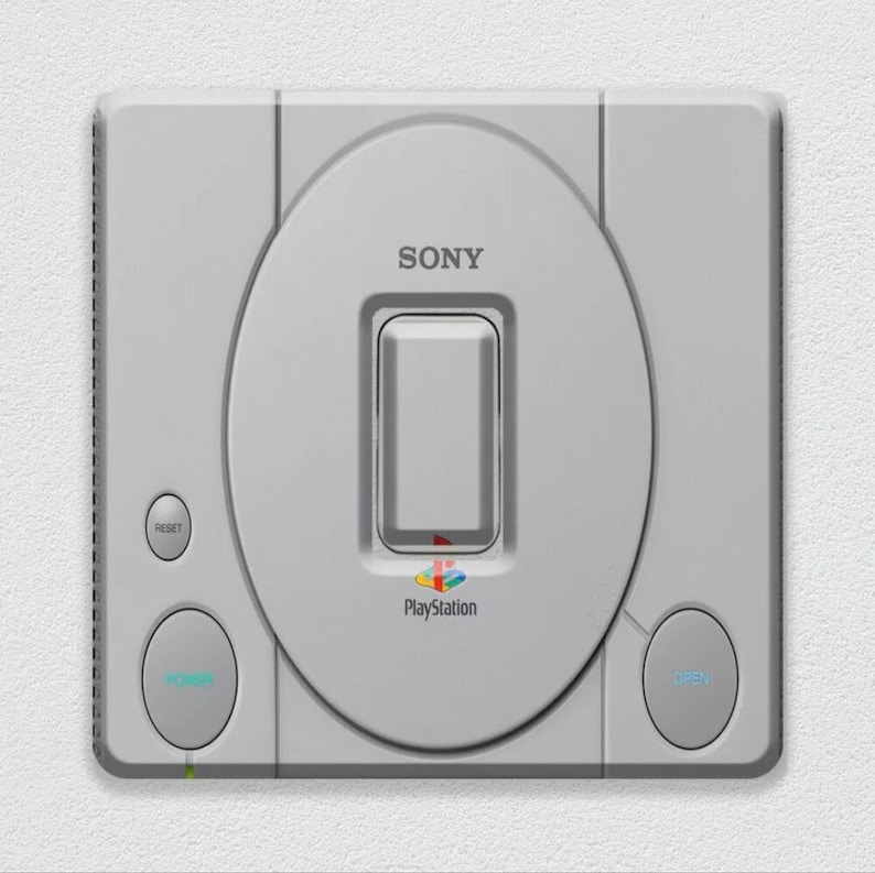May include: A white Sony PlayStation console with a gray disc drive, a power button, a reset button, and an open button. The console has the PlayStation logo and the text "PlayStation" on the front.
