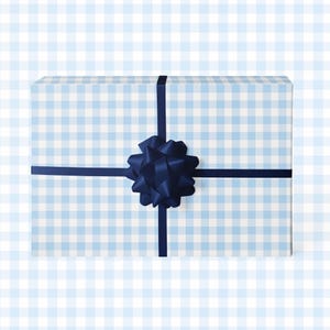 May include: A rectangular gift box wrapped in light blue and white checkered paper. A dark blue ribbon crosses the top and is tied with a large bow. The background is a light blue and white checkered pattern.