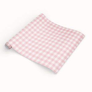 Puede incluir: Un rollo de papel de regalo con estampado de cuadros vichy rosa y blanco. El papel est&aacute; desenrollado, revelando el dise&ntilde;o de cuadros cl&aacute;sico. El rollo est&aacute; sobre un fondo blanco.
