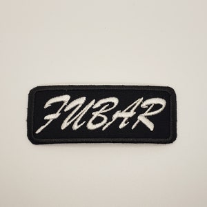 May include: A black rectangular patch with white embroidered text that reads "FUBAR".
