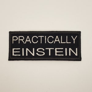 May include: Black embroidered patch with white text that reads "Practically Einstein".