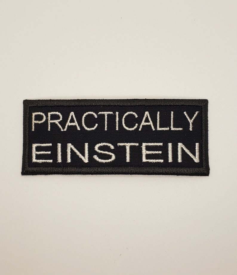 May include: Black embroidered patch with white text that reads "Practically Einstein".