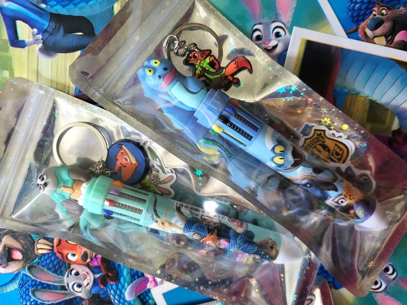 Pu&ograve; includere: Diverse penne e portachiavi a tema Zootropolis in confezioni di plastica trasparente. Le penne sono blu e verde acqua con disegni di personaggi. I portachiavi presentano personaggi dei cartoni animati.