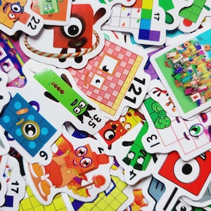 May include: A collection of colorful number-themed flashcards. The cards feature cartoon characters representing numbers, with bright colors and bold outlines. Numbers are displayed prominently on each card, with various shapes and patterns.
