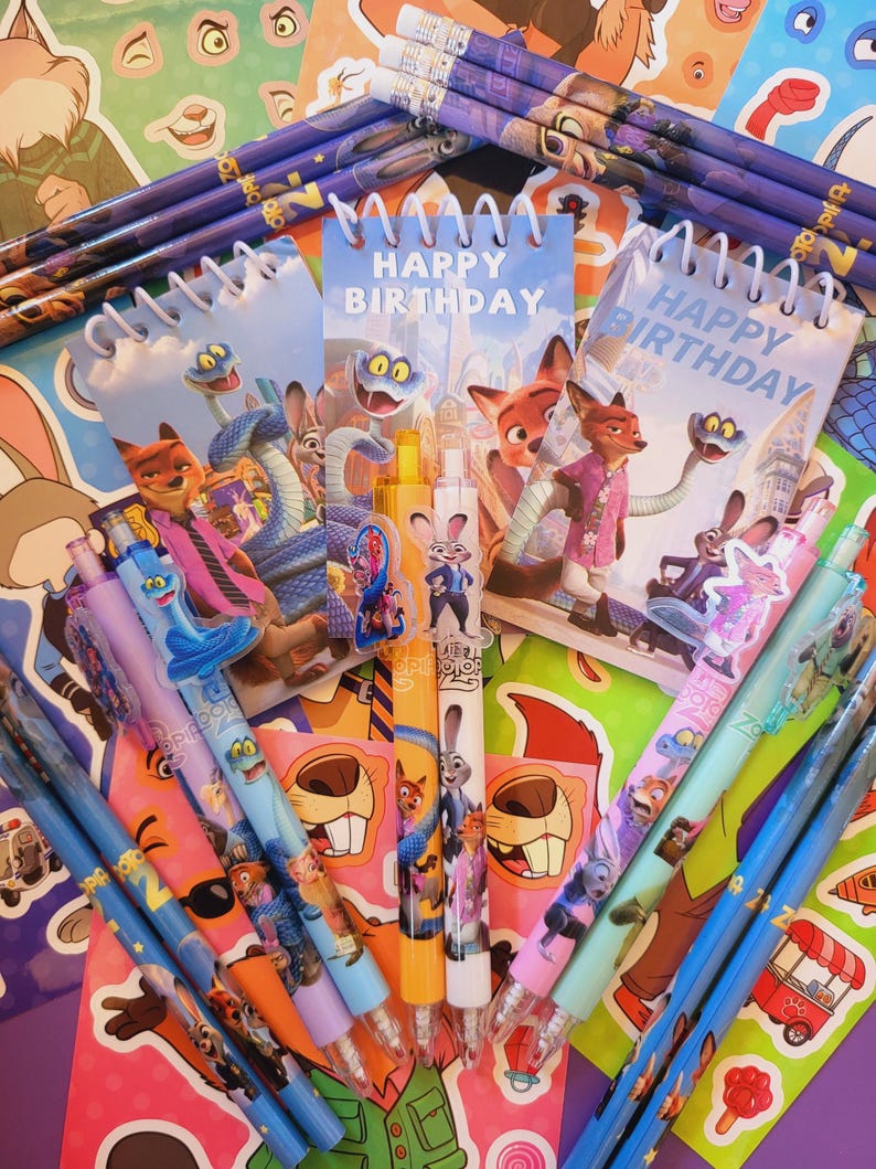 Op de afbeelding: Een collectie Zootopia-thema schrijfwaren, waaronder spiraalblokken met de tekst Happy Birthday, diverse pennen met karakter-toppers en potloden. De items zijn voorzien van kleurrijke illustraties van Nick Wilde, Judy Hopps en andere figuren.