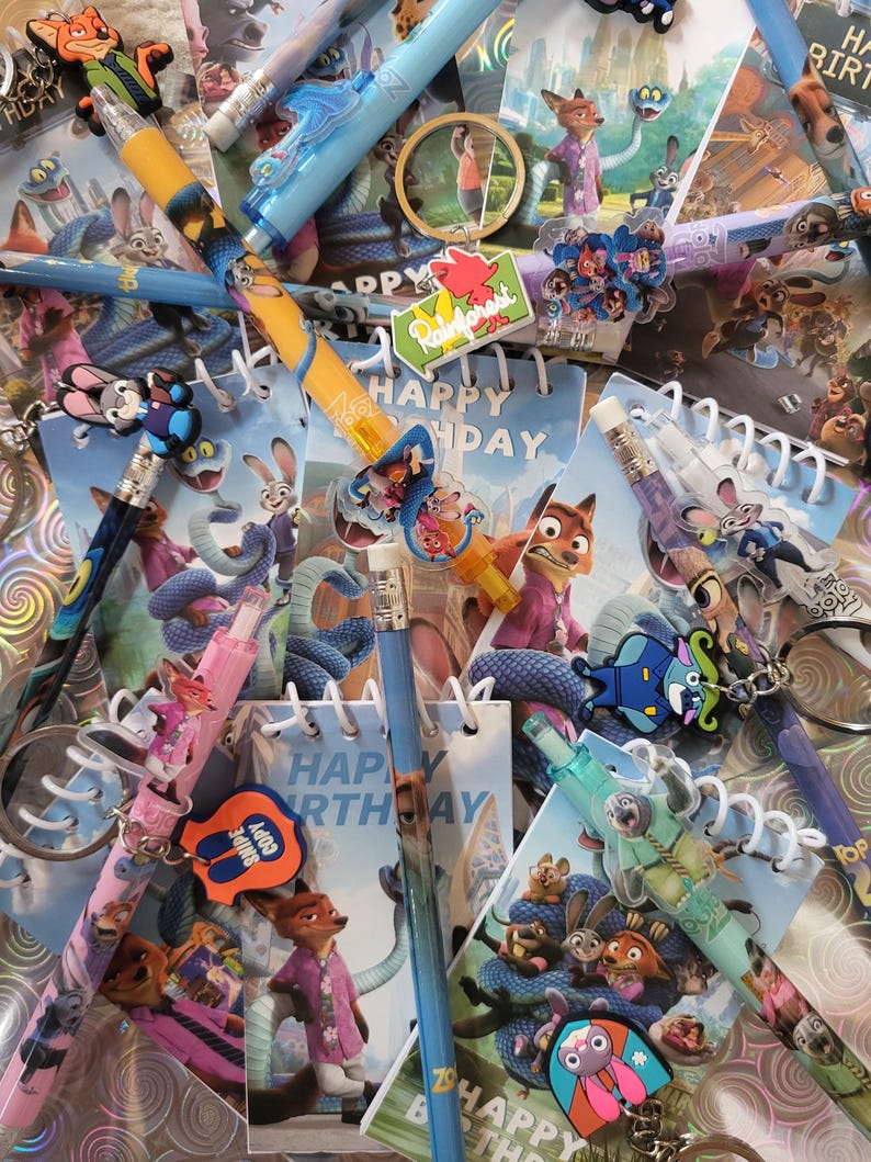 May include: A selection of Zootopia-themed stationery items, including pencils, keyrings, and small notebooks. The pencils have character toppers and colourful designs. The notebooks display "Happy Birthday". Keyrings with character designs are also present.