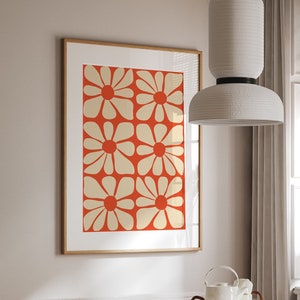 May include: A dining room with a white table with a white and gold mosaic top. The table has four chairs with woven cane seats and backs. A white pendant light hangs above the table. A framed print with a red background and white flowers hangs on the wall.