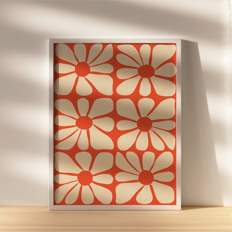 May include: A framed print with a repeating pattern of stylized white flowers on an orange background.