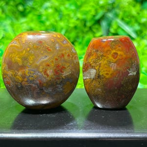 May include: Two agate stones, one round and one oval, with a brown, red and yellow colour pattern.
