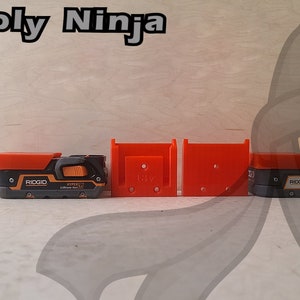 May include: Three 3D printed orange and black tool holders for a Ridgid power tool. The holders are designed to be mounted on a wall or shelf.