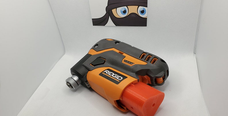 Puede incluir: Un taladro inal&aacute;mbrico negro y naranja con una bater&iacute;a roja. El taladro tiene el logotipo de RIDGID en el lateral.