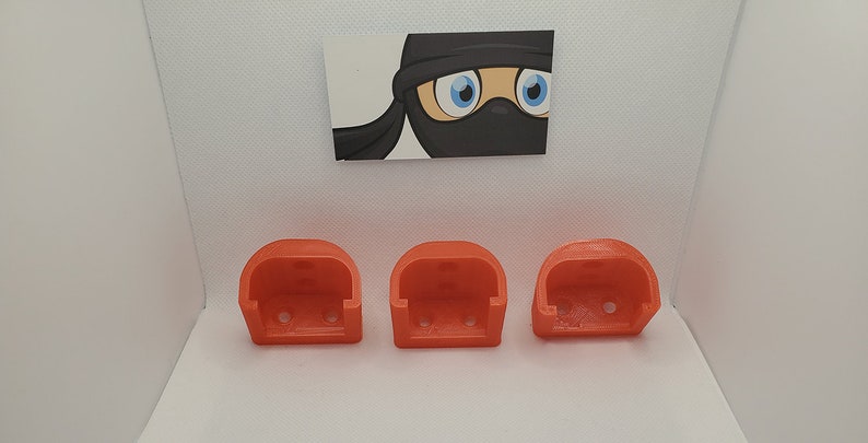 May include: Three bright orange plastic wall mounts, each with three holes for mounting screws.