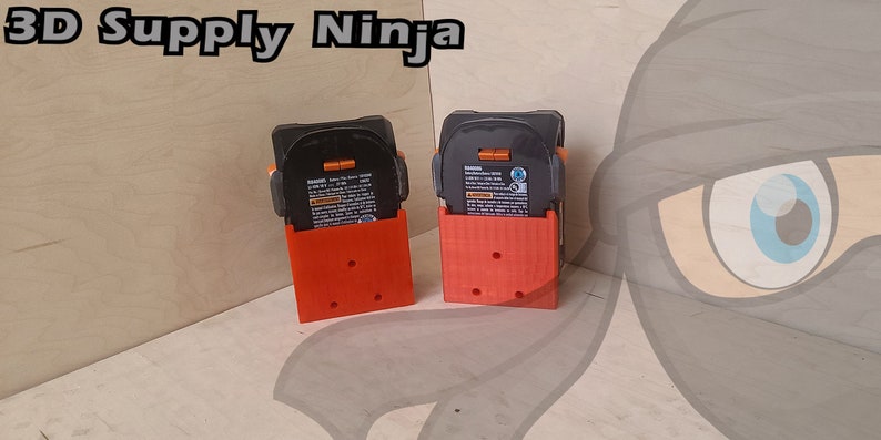 May include: Two 3D printed orange battery holders with black batteries inside. The holders have a textured surface and are designed to hold batteries upright. The text "3D Supply Ninja" is visible in the top left corner of the image.