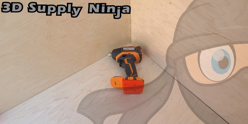 Pu&ograve; includere: Un trapano a batteria nero e arancione con un cacciavite a percussione rosso su una superficie di legno. Il trapano ha la scritta "RIDGID" stampata su di esso.