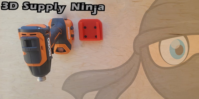 Pu&ograve; includere: Un trapano a batteria nero e arancione con una punta argentata, montato su un supporto a parete rosso stampato in 3D. Il testo "3D Supply Ninja" &egrave; visibile nella parte superiore dell'immagine.