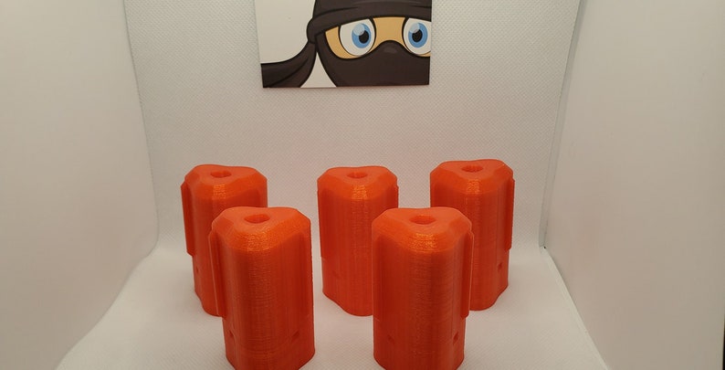 Puede incluir: Seis piezas de pl&aacute;stico naranja brillante impresas en 3D con un dise&ntilde;o &uacute;nico. Las piezas tienen forma de cilindro con una parte superior e inferior redondeadas. Tienen una superficie texturizada y un agujero en el centro.