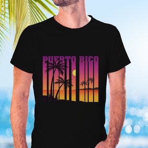 Puede incluir: Una camiseta negra con un diseño gráfico de palmeras y una puesta de sol con el texto "PUERTO RICO" en estilo retro.