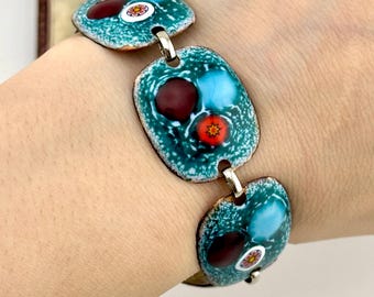 Puede incluir: Pulsera vintage con tres eslabones rectangulares de esmalte turquesa, unidos por conectores plateados. Cada eslabón tiene un diseño único con detalles en rojo, azul y blanco. Una pieza de joyería única.