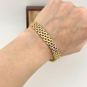 May include: A gold-toned bracelet featuring a multi-row link design with small, rectangular, polished segments arranged in a repeating pattern. The bracelet has a flexible structure that wraps around the wrist, showcasing a bright, metallic finish.