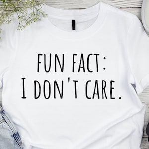 May include: White t-shirt with black text that reads "Fun Fact: I Don't Care."