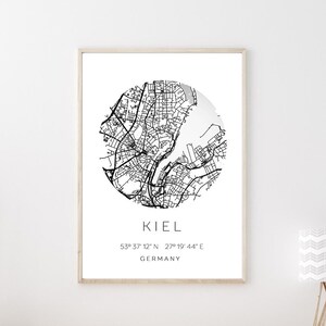 Könnte beinhalten: Ein Schwarzweiß-Kartenprint von Kiel, Deutschland, mit dem Namen der Stadt und den Koordinaten darunter. Der Druck ist gerahmt und hängt an einer weißen Wand über einem Holz-Konsolentisch.