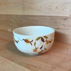 May include: A white ceramic mixing bowl with a floral pattern in shades of orange, yellow, and brown. The bowl has a fluted design and is perfect for mixing ingredients.