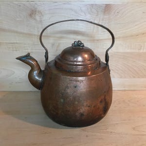 May include: Antique copper kettle with a rounded body, a lid with a decorative knob, and a curved handle.