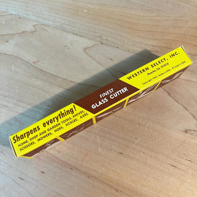 May include: A yellow and brown box for a glass cutter. The box has text that reads "Finest Glass Cutter" and "Sharpens everything!" It also lists various tools. The box is from Western Select, Inc.