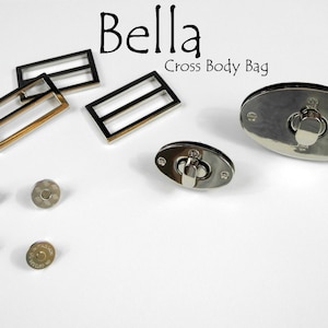 May include: Silver-toned metal hardware for a cross-body bag. The hardware includes two oval-shaped magnetic closures, four small round metal pieces, and three rectangular metal buckles.