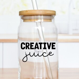 May include: A clear glass jar with a wooden lid and a straw. The jar has the text "CREATIVE juice" written on it.
