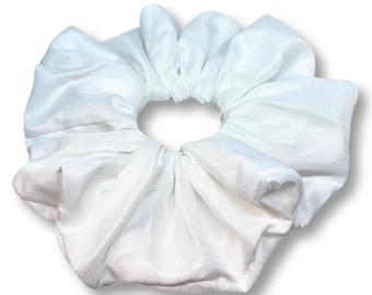 May include: A white scrunchie made of soft fabric. The scrunchie is gathered into a large, round shape.