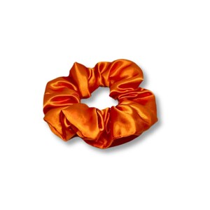 May include: A bright orange satin scrunchie for hair.