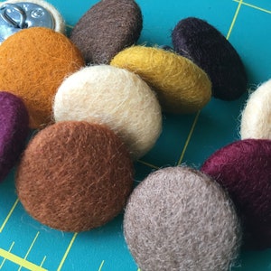 Peut inclure: Assortiment de boutons ronds en feutre de différentes couleurs, dont le brun, le beige, le bordeaux et le jaune moutarde.