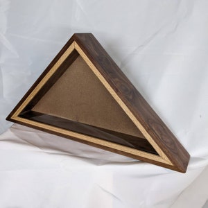May include: Triangular wooden display case with a dark brown exterior and a lighter wood trim. The interior features a tan backing, and the case is designed to hold a flag. The case is set against a white background.