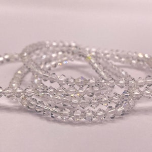 Puede incluir: Una hebra de cuentas de cristal transparente, con una forma facetada, similar a un diamante. Las cuentas están enhebradas para formar una hebra larga y continua.
