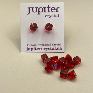 Könnte beinhalten: Eine Gruppe von 10 roten Kristallwürfeln, mit zwei kleineren Würfeln auf einer weißen Karte mit dem Text "jupiter crystal" und "Vintage Swarovski Crystal jupitercrystal.ca"