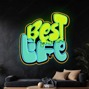 May include: A neon sign with the words "Best Life" in a graffiti-style font. The word "Best" is in lime green with a dripping effect, and "Life" is in a teal color. The sign has a black background and is mounted on a wall.