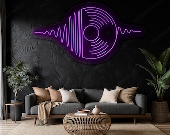 Può includere: Un'insegna al neon viola a forma di disco in vinile con onde sonore. L'insegna è montata su una parete nera con un motivo strutturato. La stanza presenta un divano grigio, un tavolino intrecciato e piante.