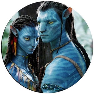 Può includere: Un primo piano di due personaggi dalla pelle blu del film Avatar. I personaggi sono in piedi uno accanto all'altro, con la donna a sinistra e l'uomo a destra. Entrambi hanno capelli lunghi e scuri e grandi occhi gialli. La donna indossa una collana e una varietà di altri gioielli, mentre l'uomo indossa una collana e una cinghia sul petto.
