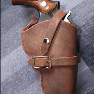 May include: A brown leather holster with a belt loop and a snap closure. A revolver is inside the holster.