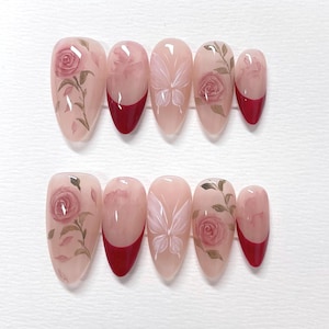 May include: Set of ten false nails with a red tip and a floral design. The design features pink roses, leaves, and a butterfly.