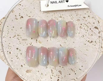 Op de afbeelding: Een set kunstnagels met een gradiëntontwerp in pastelroze, geel en blauw. Elke nagel heeft een subtiel sterrenpatroon. Het label luidt "NAIL ART" en "To beautiful you".