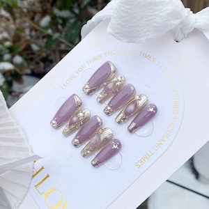 Peut inclure: Ensemble de dix faux ongles violets et argent&eacute;s avec des strass et un accent nacr&eacute;. Les ongles sont pr&eacute;sent&eacute;s sur une carte blanche avec le texte "I love you three thousand times I love you three thousand times".