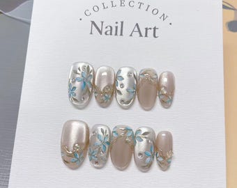 Uñas postizas reutilizables con diseño floral azul claro hechas a mano.