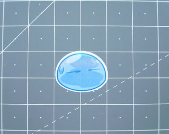May include: A blue slime character with a simple face, a sticker on a gray background.