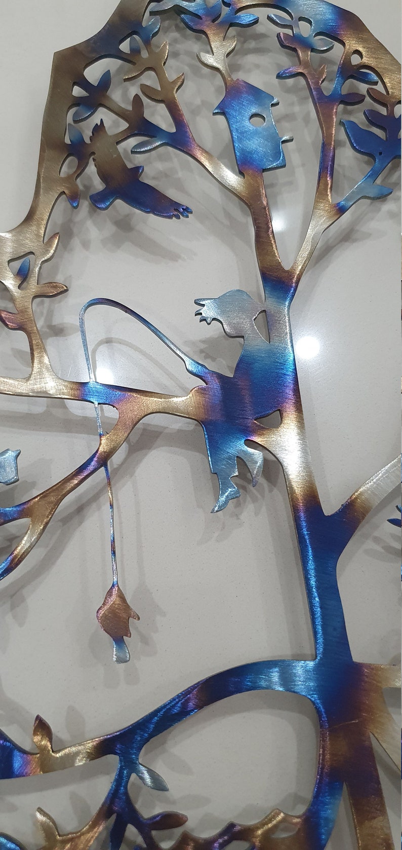 Puede incluir: Una escultura de pared de metal de un &aacute;rbol con una ni&ntilde;a sentada en una rama y pescando. El &aacute;rbol est&aacute; hecho de metal y tiene un acabado azul y dorado. La ni&ntilde;a tambi&eacute;n est&aacute; hecha de metal y tiene un acabado azul.