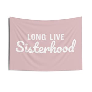 May include: A pink tapestry with the text "Long Live Sisterhood" in white cursive lettering.